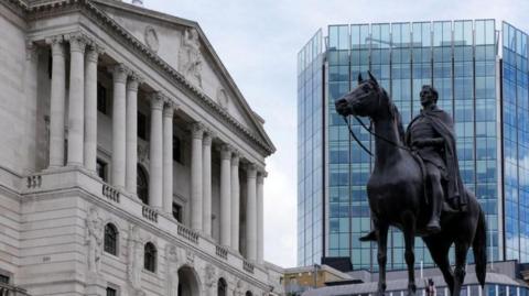 A photograph of the outside of the Bank of England building. A statue of a man on a horse is also visible in the shot. 