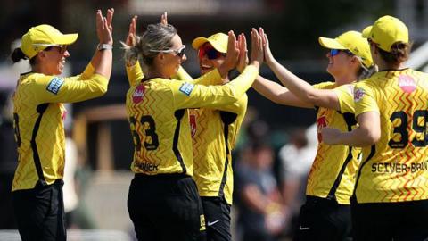 Trent Rockets players, wearing yellow tops and black trousers, celebrate a wicket