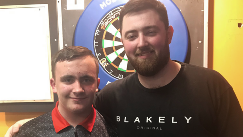 Luke Littler and Luke Humphries in front of a dart board