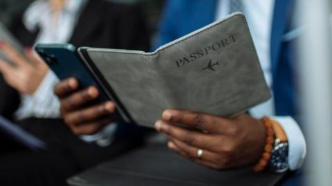 A man holding a book cover that says "passport".