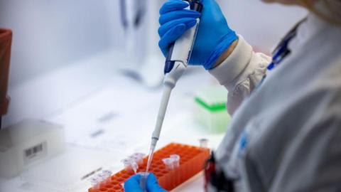 A person uses a pipette in a lab