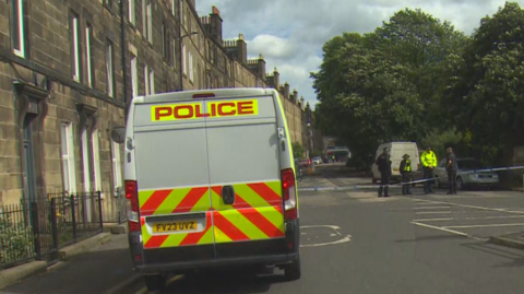 Police van and police tape outside flat where body was found.