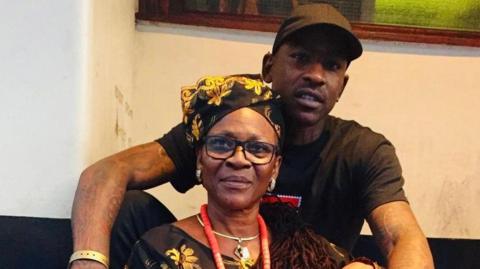 Skepta sits behing his mum Ify Adenuga