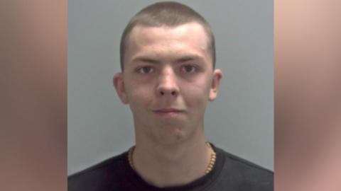 Elvis Price is wearing a black T-shirt with a shaved head and is looking directly at the camera. 