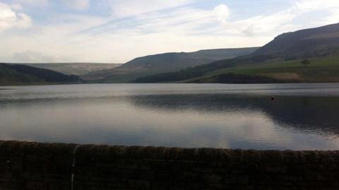 Dovestone Reservoir showing the reservoir with mountains and hills in the background on a clear day.