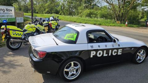 A sports car with the livery of a Japanese police vehicle