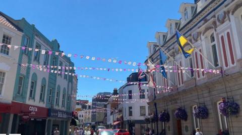 St Helier's high street with flags above the road and a sign saying Costa and Bella Italia