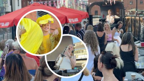 A group of men and women dancing to a DJ in a raised container. Behind them is Union Jack bunting and wide red parasols. To their left is two circular cut outs, one lady is in yellow and gold with a flower hat on and large fan. The other is a woman with ginger hair and a gold saxophone in her mouth, she leans back to play it.