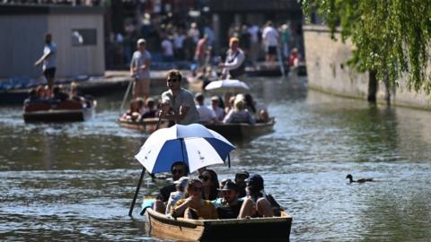 A busy River Cam in Cambridge with umbrellas shading boat-trippers from the Sun
