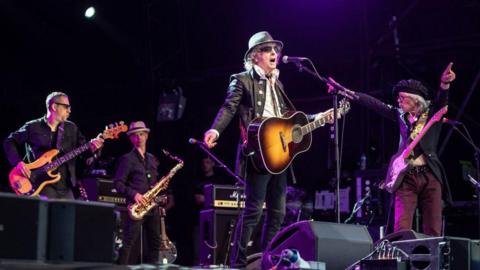 Paul Page, James Mastro, Ian Hunter and Ariel Bender of Mott The Hoople performing live on stage. Hunter is at a microphone 