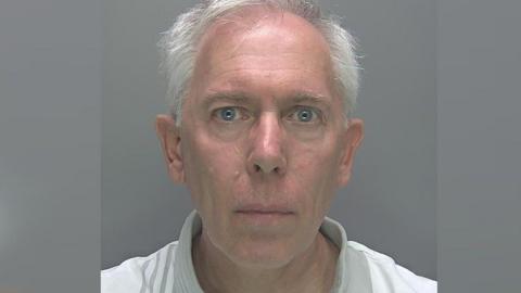 Anthony Goodridge, who has grey hair, and is wearing a white top with a grey collar