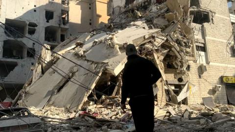 A man inspects the debris and damage at the site of overnight Israeli airstrikes that targeted Beirut's southern suburb of Hadath on 27 October 2024