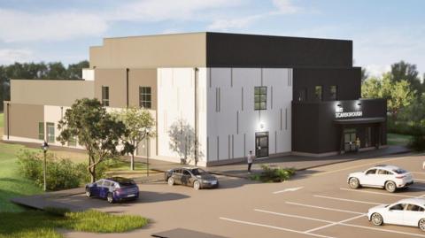 Design image of a modern white‑and‑grey NHS Scarborough building with parked cars in front and a few people walking near the entrance, surrounded by landscaped greenery and trees.