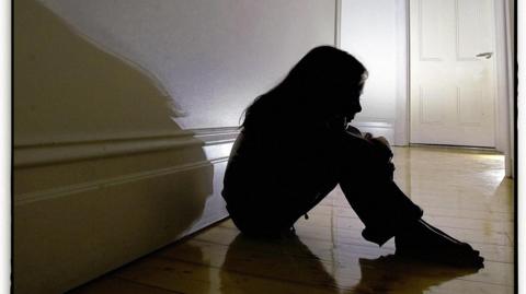 A silhouette of a woman sitting in the hallway. 