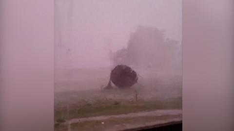 A trampoline blowing away in the wind, with torrential rain