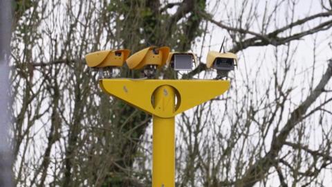 A picture of a yellow speed camera with four different cameras - two facing each way.