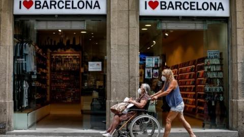 A woman pushes a wheelchair in downtown in Barcelona