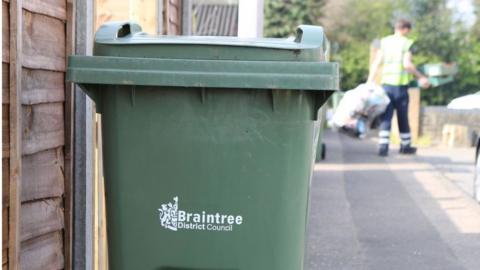 A green garden waste collection bin