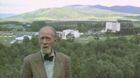 Fyfe Robertson stands in the Highlands with the Aviemore centre in the background