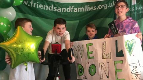 Taylor Hardy surrounded by his brothers on cycling machine