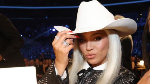 Beyonce, wearing a white cowboy hat, pouts at the camera