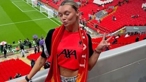 Ellie-Ann Prendergast posing at a football stadium wearing fashionable Liverpool football fan gear.