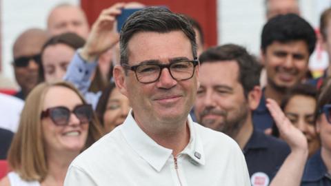 Andy Burnham dressed in a white shirt and wearing his black rimmed glasses