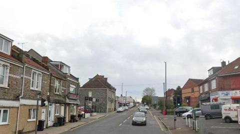 Two Mile Hill with a little bit of traffic on the right hand side. It's an overcast say and there is one person walking on the pavement on the right.