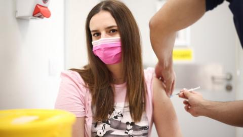 A person receives a dose of the Pfizer BioNTech vaccine at the Central Middlesex Hospital in London