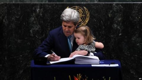US Secretary of State John Kerry signs the book holding his granddaughter