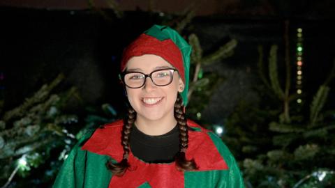 elf in front of christmas trees