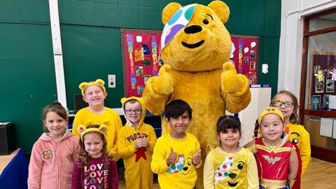 Pupils at All Saints’ Church of England Infant & Junior Academy in Hessle wearing Pudsey ears and yellow Pudsey T-shirts stand around Pudsey 