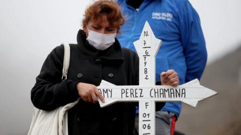 A relative of a Covid-19 victim prays in front of her grave in Lima