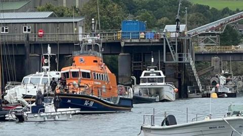 The lifeboat moored up in the harbour with several small boats moored around it