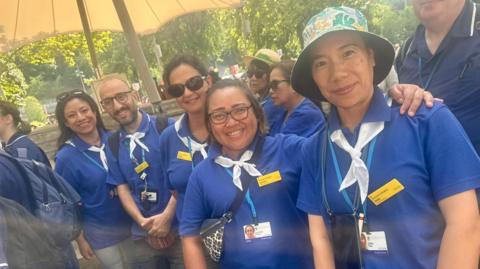 A group of student nurses lined up for the camera wearing blu shorts and white cravats
