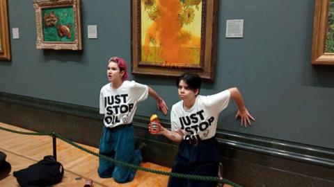 Phoebe Plummer and Anna Holland sitting in front of the Sunflowers after throwing soup on it.