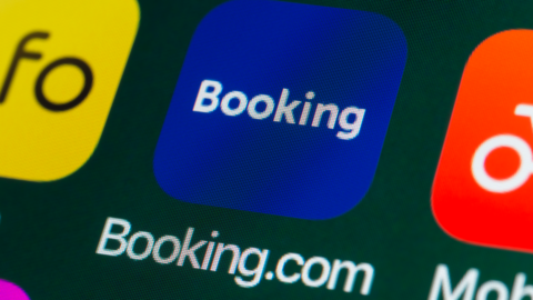 The icon of the travel app Booking.com, surrounded by other apps on the screen of an iPhone.
