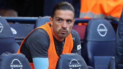 Jack Grealish sitting on a substitutes' bench