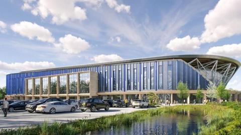 CGI image of the exterior of Oxford United's planned new stadium with cars parked outside and a pond and green area to the side