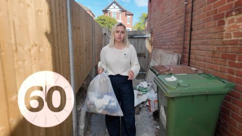 A woman with blonde hair holding a bin bag 