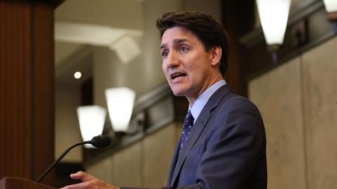 Prime Minister Justin Trudeau speaking at a podium on Parliament Hill in Ottawa, Canada. 