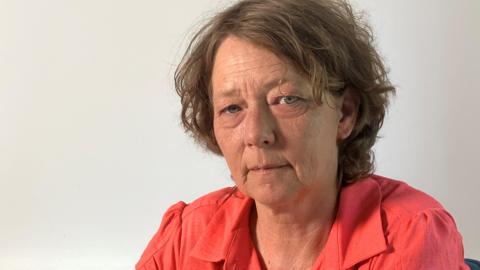 Wearing a red blouse, Samantha Gillingham stares into the camera.