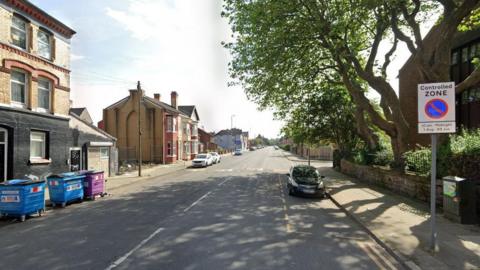 Google streetview of cars and houses on Fountains Road, with a traffic sign and large wheelie bins in the foreground