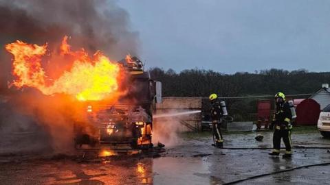 Firefighters are tackling the lorry blaze on the outskirts of Holsworthy. You can see the lorry which is well alight. One of the first responders is using a jet to tackle the blaze.