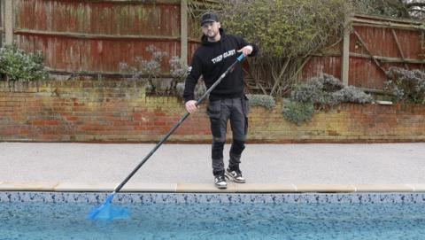 A man cleaning a swimming pool