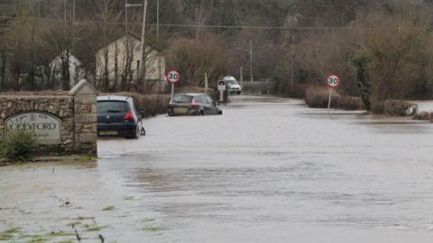 Cars half submerged in water on a road in the south west.