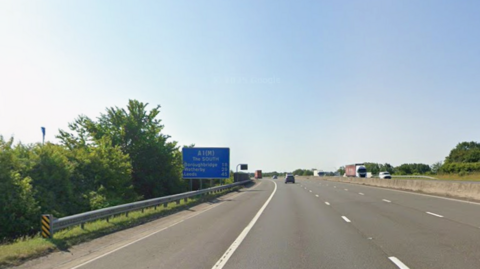 The southbound carriageway of the A1(M). It is a quite three-lane motorway. On the left is a blue sign reading: A1(M) The South Boroughbridge 18 Wetherby 29 Leeds 45