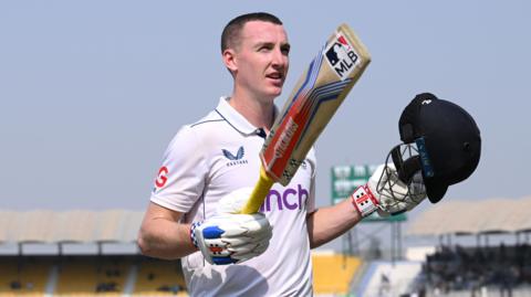 Harry Brook lifts his bat and helmet after his triple century