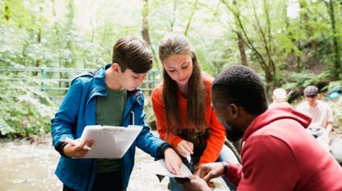 Two children and a teacher on a field trip in a wood