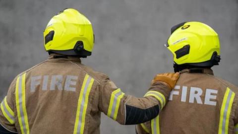 View from behind of two firemen in protective uniforms